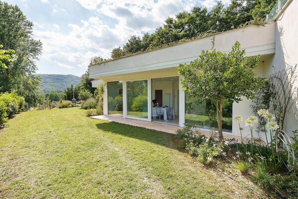 Una casa moderna con un porche cubierto, césped y un jardín lleno de flores.