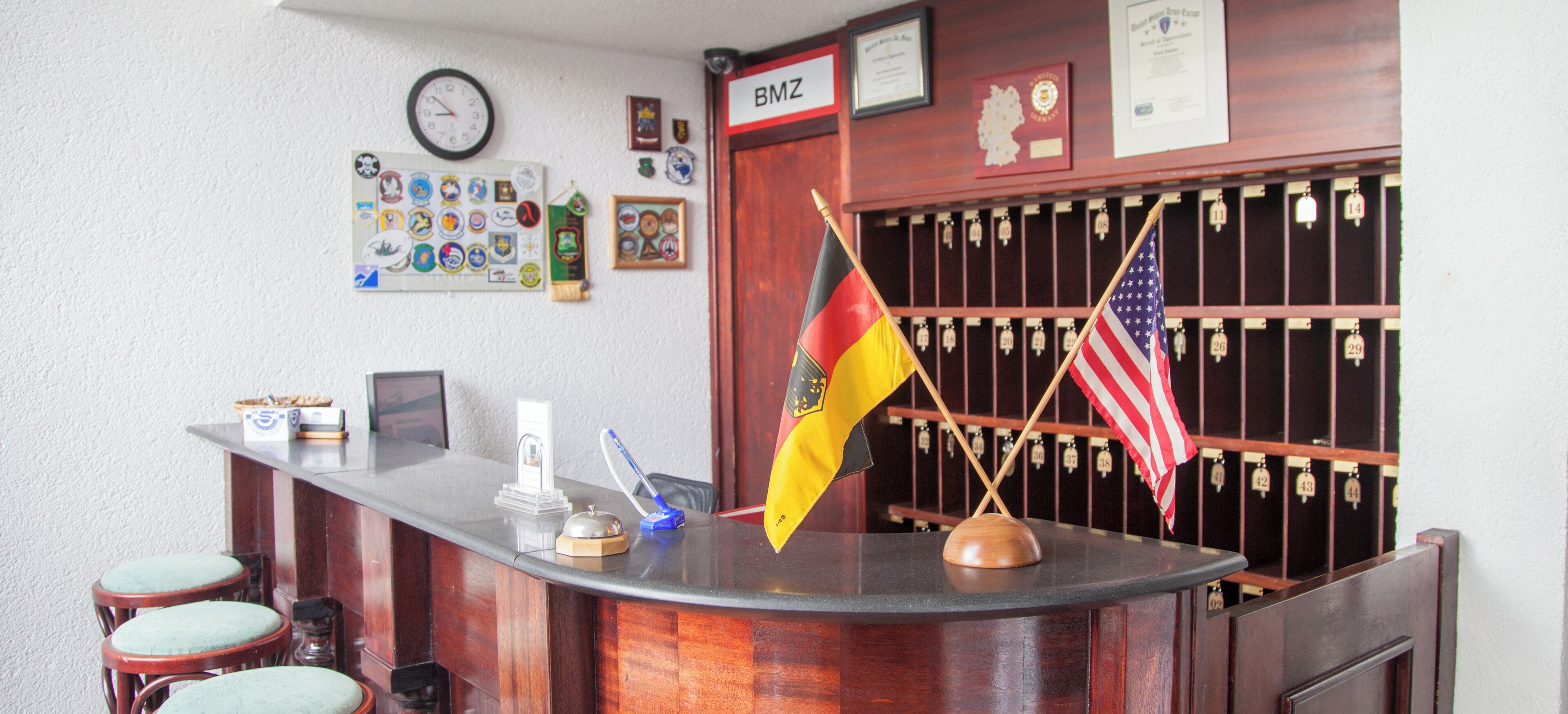 Una recepción con banderas, un reloj y varios premios en la pared.