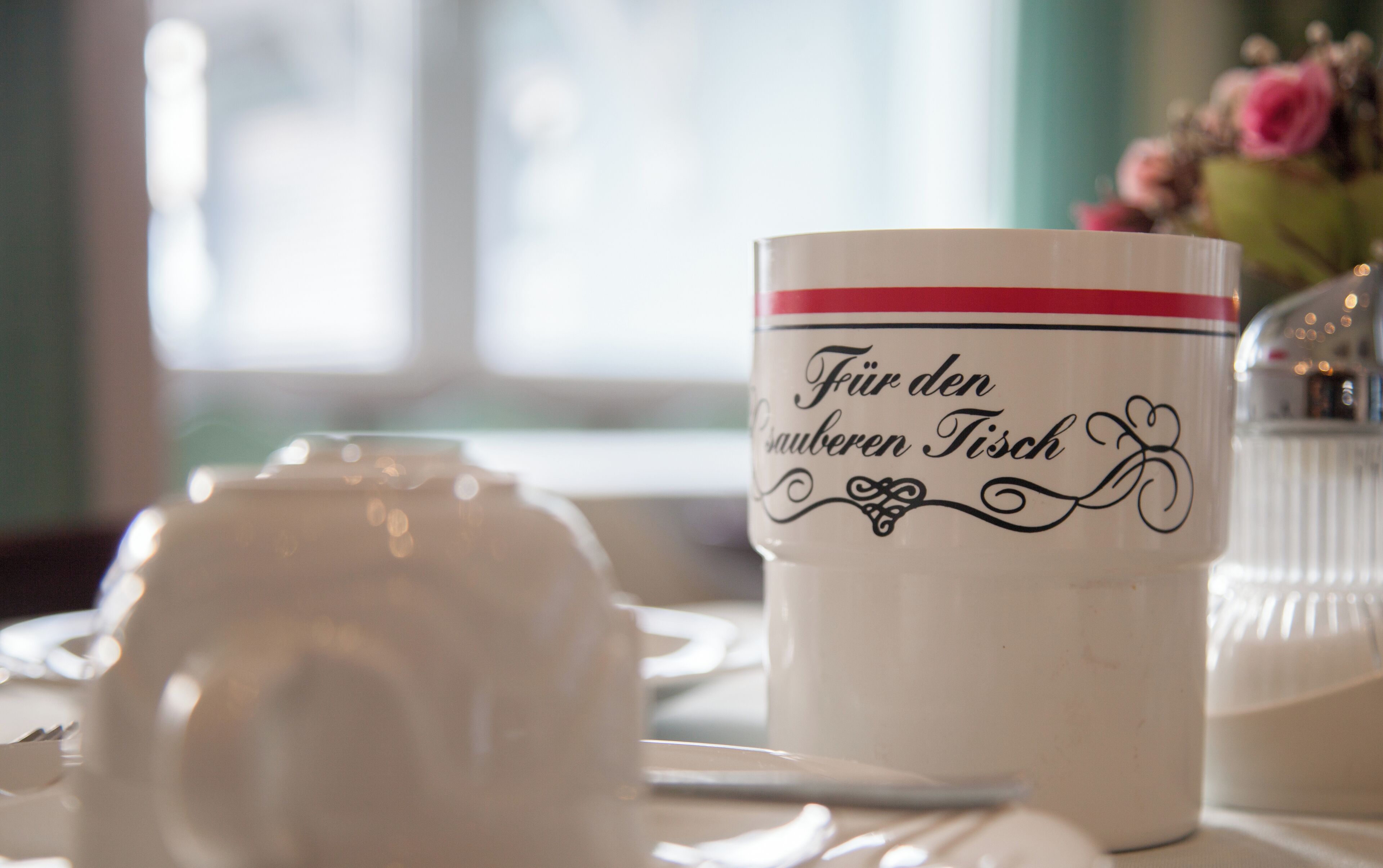 A table setting with a white teapot and a mug with text.