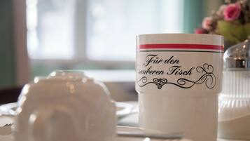 A table setting with a white teapot and a mug with text.