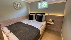 A bedroom with a bed, a wall clock, a window, and an air conditioning unit. - Five Studios - Premium Rooms (Ramstein-Miesenbach)