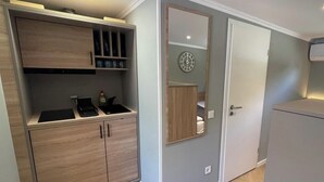 A compact kitchen with built-in cabinets, a countertop, and a wall-mounted mirror. - Five Studios - Premium Rooms (Ramstein-Miesenbach)