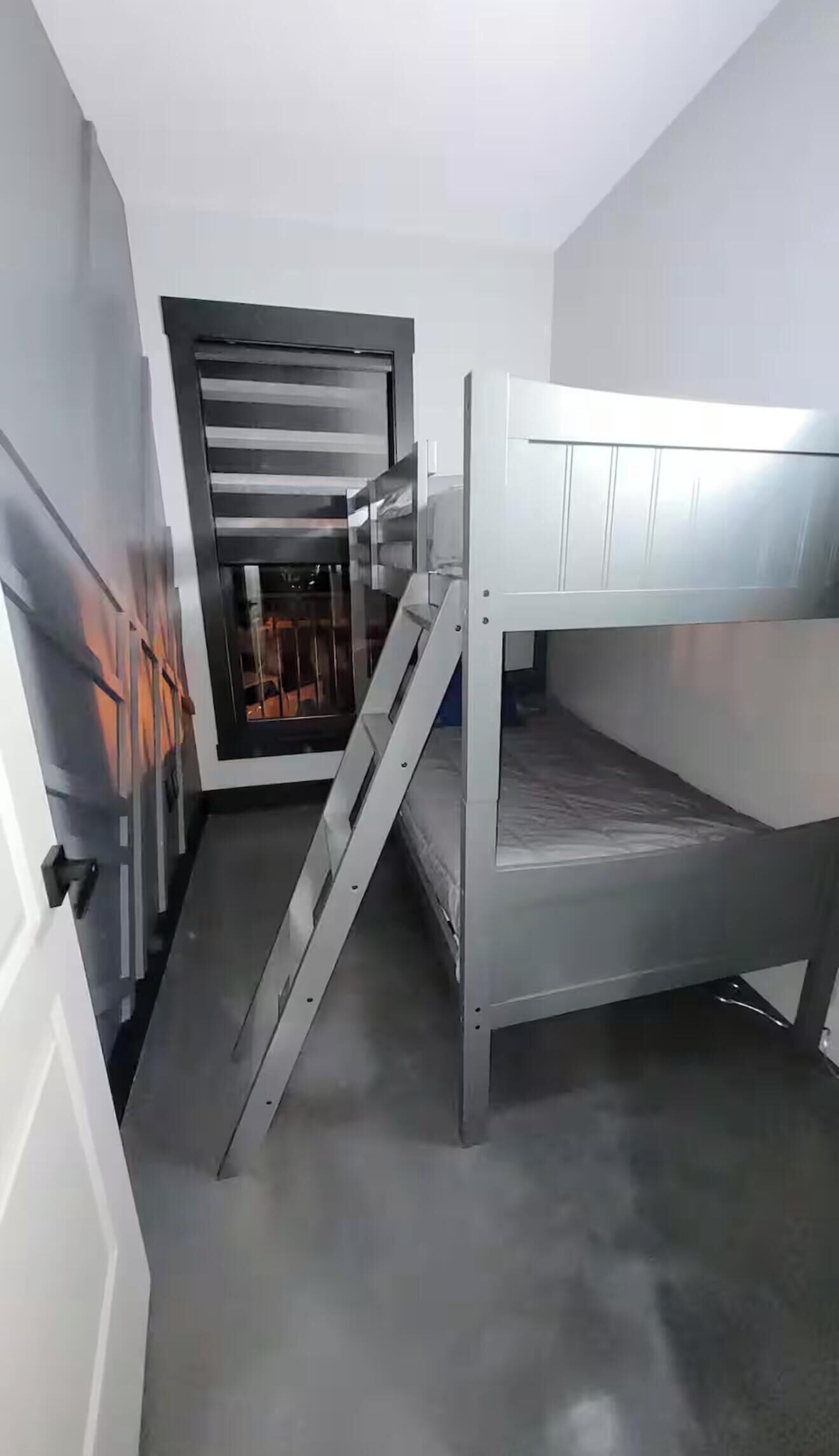 Un lit superposé avec une échelle, une porte et une fenêtre.