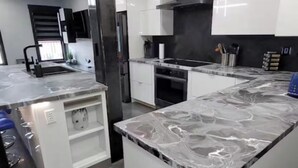 Una cocina moderna con armarios blancos, una isla central y electrodomésticos de acero inoxidable.