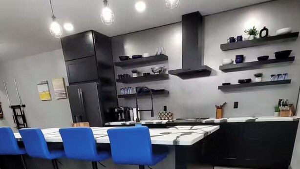 A modern kitchen with a central island, bar stools, and built-in shelves.