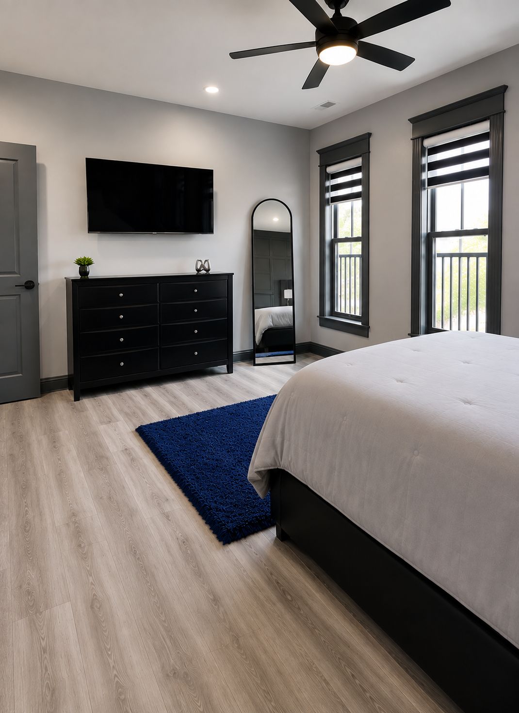 Un dormitorio con cama, cómoda, televisor, ventilador de techo y ventana.