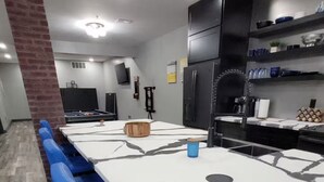 A modern kitchen with a large island, blue bar stools, and a brick accent wall.