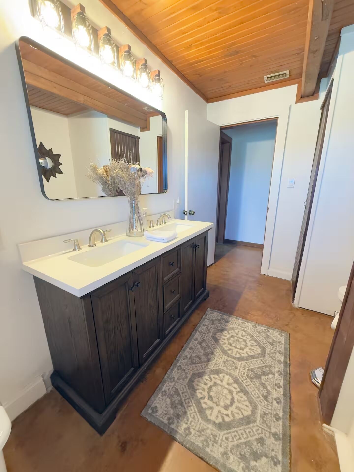 A bathroom with a double sink vanity, a large mirror, and a decorative vase.