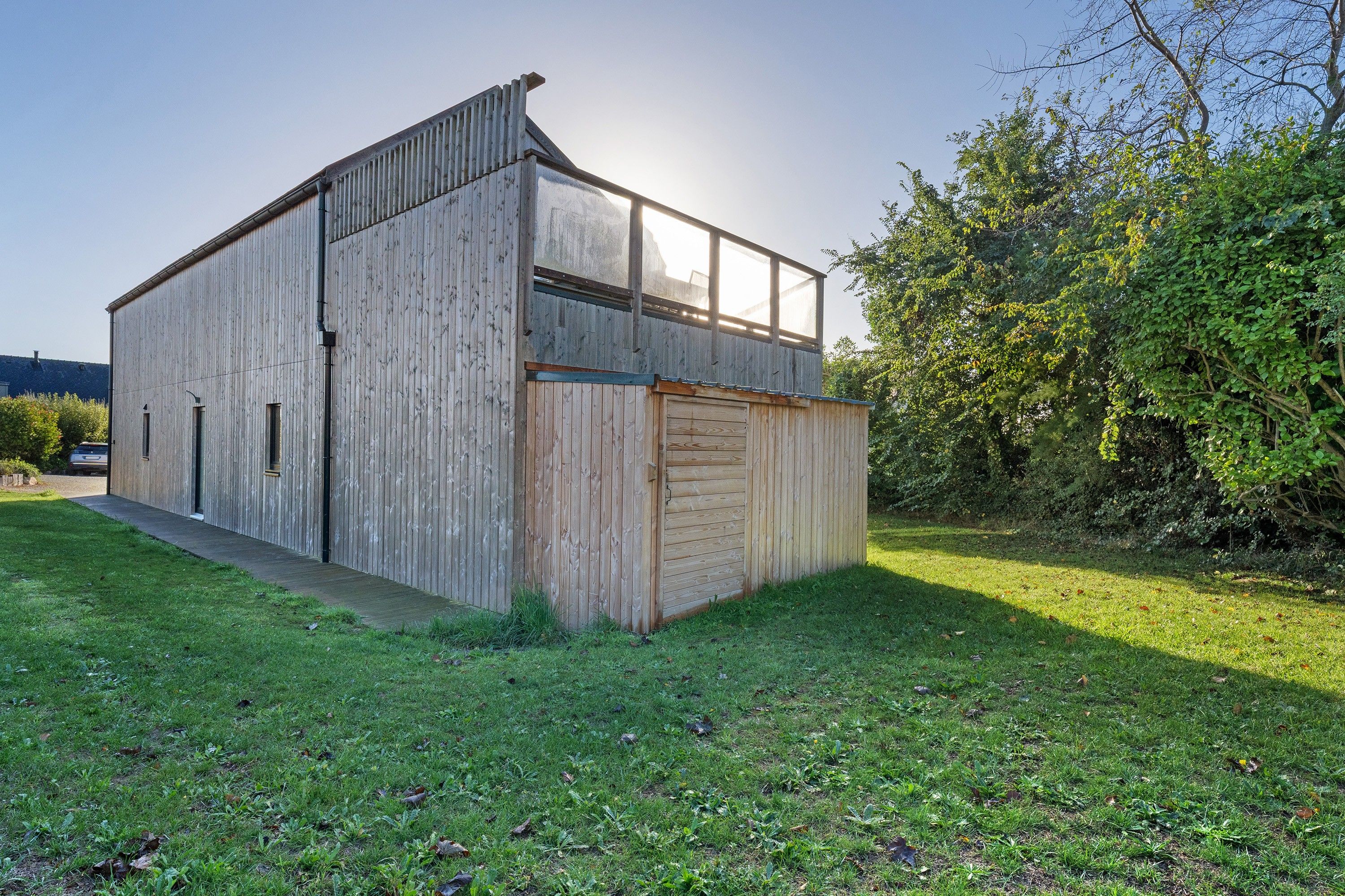 A two-story wooden building with a flat roof and a large window on the upper floor.