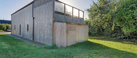 A two-story wooden building with a flat roof and a large window on the upper floor.