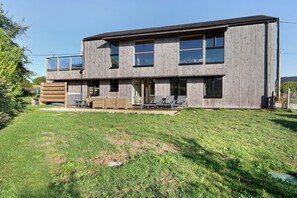 A two-story wooden house with a flat roof, large windows, and a covered patio area with outdoor furniture. - Villa Grande Est, Private Spa, Ideal for Family Holidays (Plouneour-Trez)