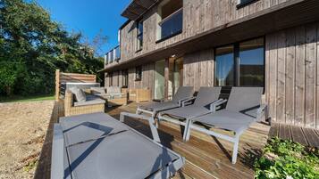 A wooden deck with lounge chairs and a hot tub.