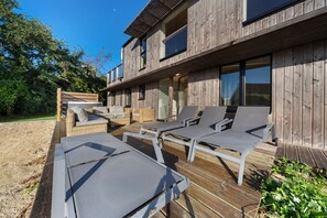 A wooden deck with lounge chairs and a hot tub.