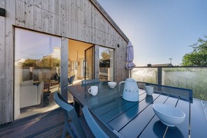A wooden deck with a table set for two, a kettle, and a bowl. - Villa Grande Est, Private Spa, Ideal for Family Holidays (Plouneour-Trez)