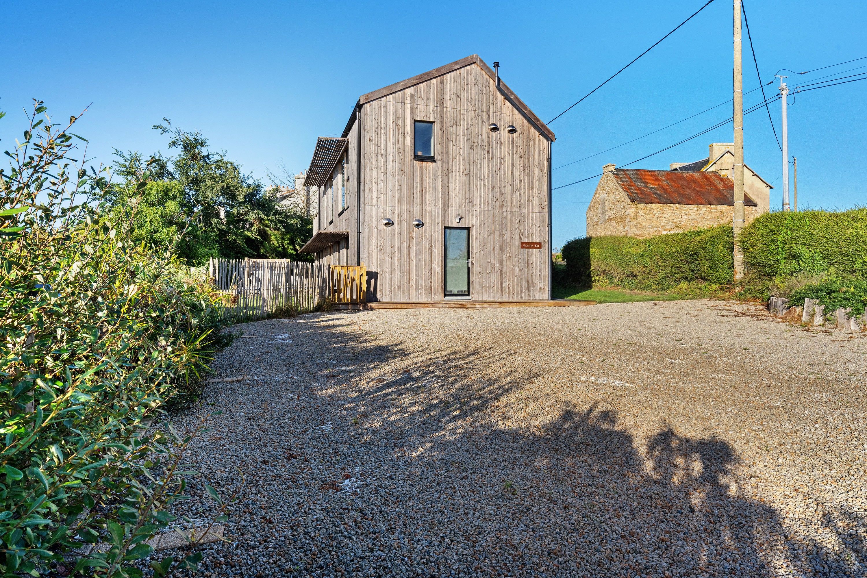 A wooden barn with a gravel driveway leading to a wooden gate.