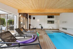 Ein Poolbereich mit Liegestühlen, einem Schwimmbecken und einer Holzdecke.