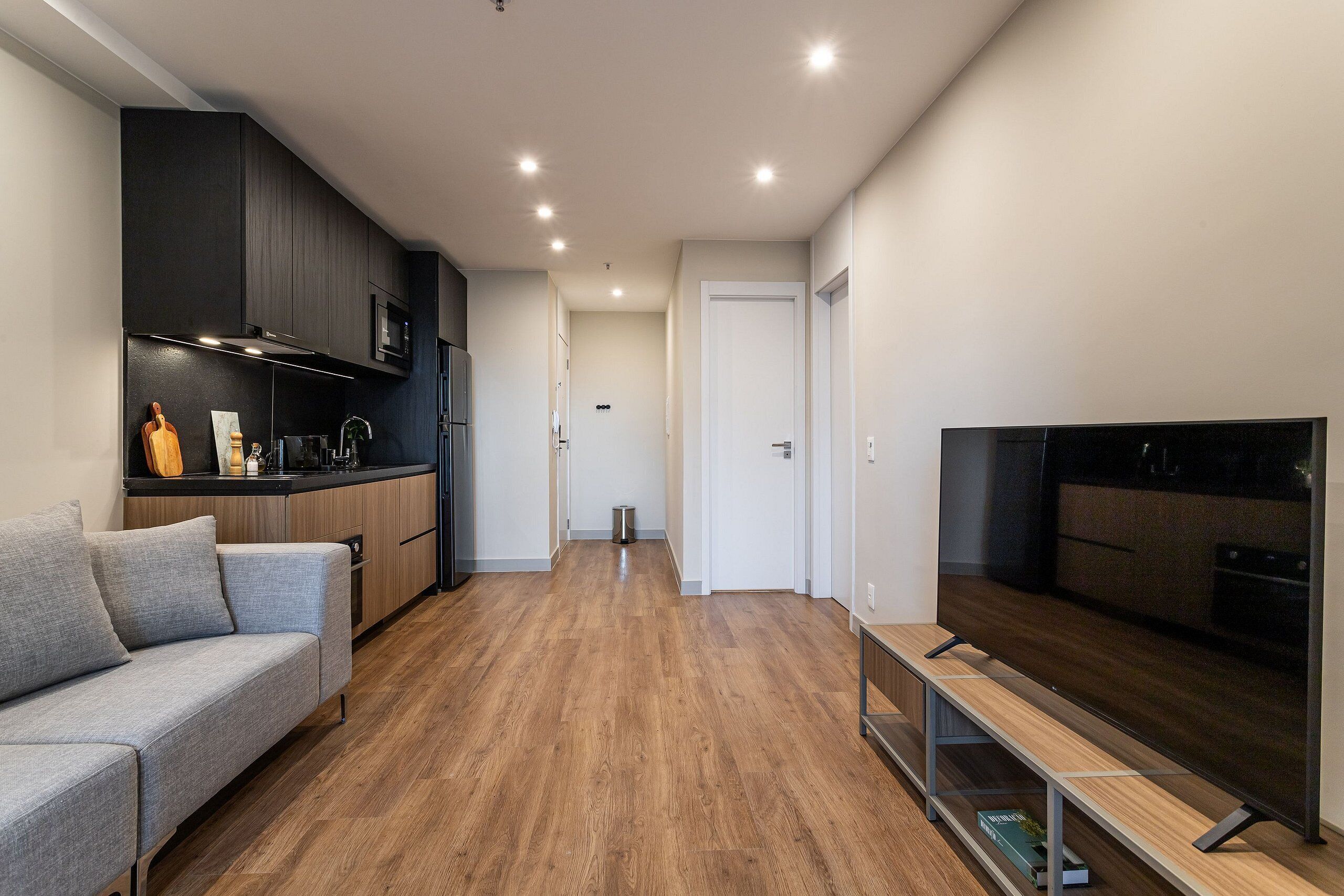 A modern kitchen with dark cabinets, a built-in microwave, and a wooden countertop.