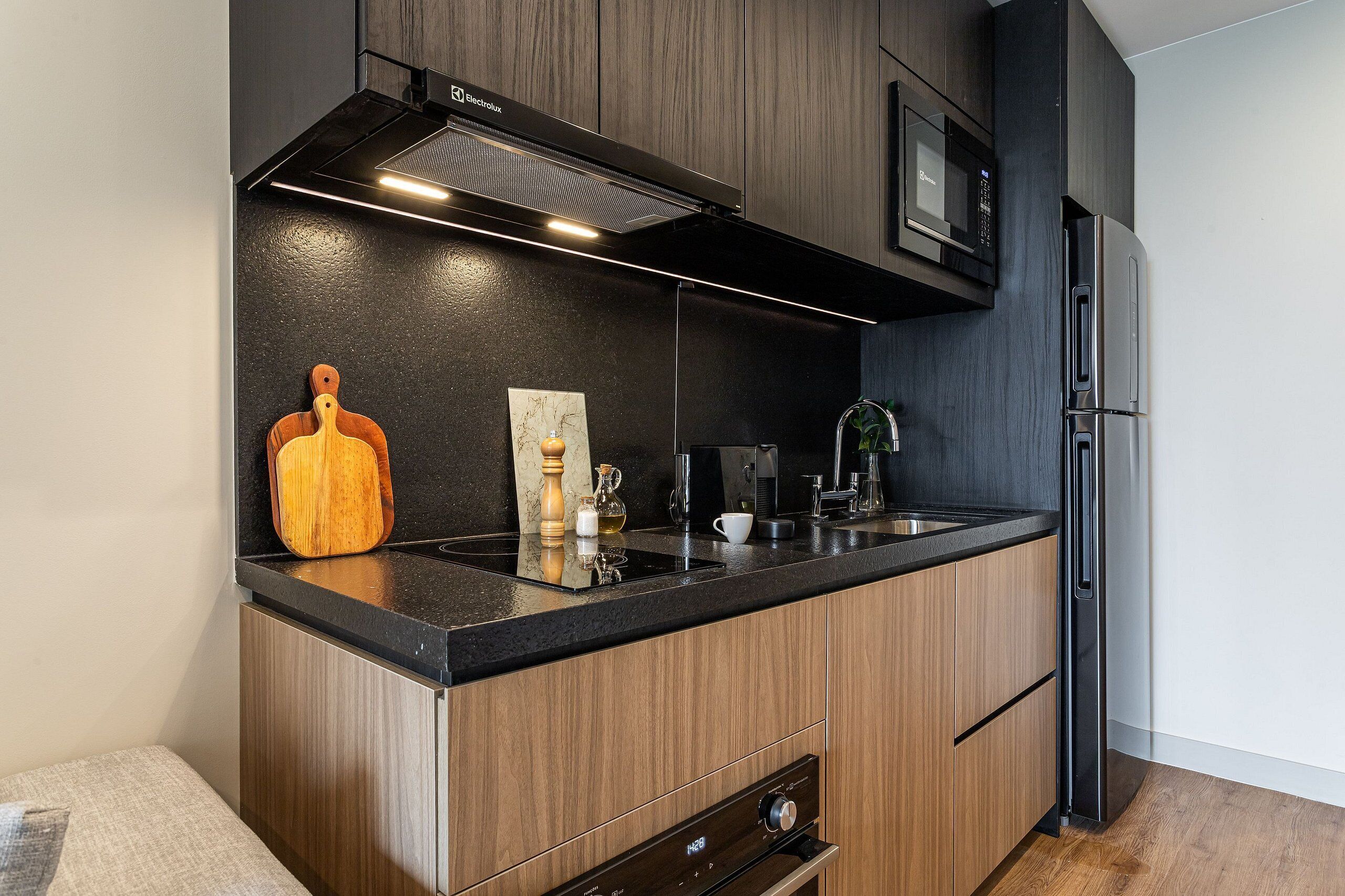 A modern kitchen with a built-in microwave, stainless steel appliances, and wooden cabinetry.