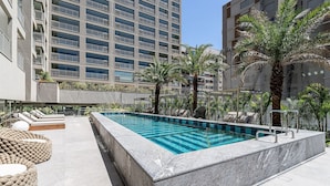 A rooftop pool with lounge chairs and palm trees. - Sofisticação e conforto no bairro mais charmoso da cidade - Moema (São Paulo)