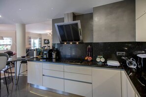 Cozinha moderna com bancada preta, armários brancos e micro-ondas embutido.