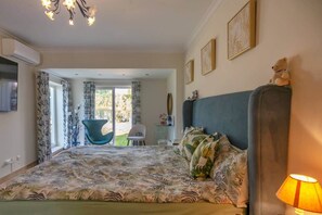 A bedroom with a bed, a chair, a lamp, and a view of the outdoors.