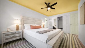 A bedroom with a bed, nightstands, a ceiling fan, and a striped floor. - Bright Bay Hideaway • Springs • Pets Welcome (Crystal River)