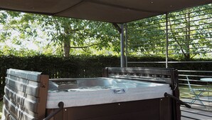 Un jacuzzi exterior con toldo, escalones y baranda de metal.