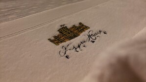 Una cama bien hecha con una colcha blanca y un cojín decorativo bordado.
