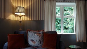 Una habitación con sofá, lámpara y ventana con cortinas.
