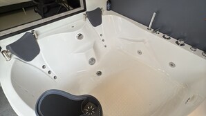 A modern bathroom with a large bathtub, a mirror, and a wooden headboard. - Biofilia Monteverde (Monteverde)