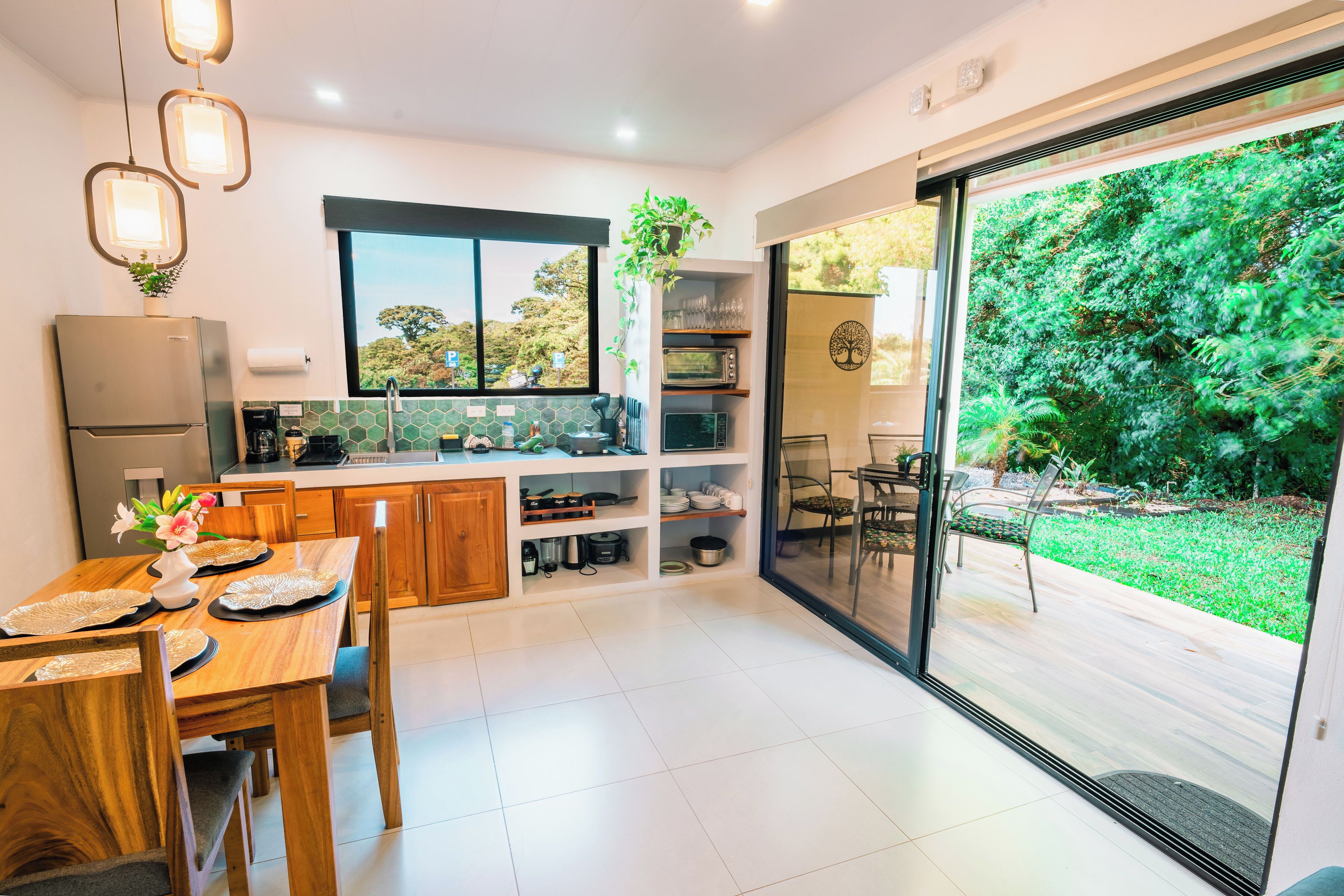 Cocina moderna con comedor, horno empotrado y un amplio ventanal corredera que da a un jardín.