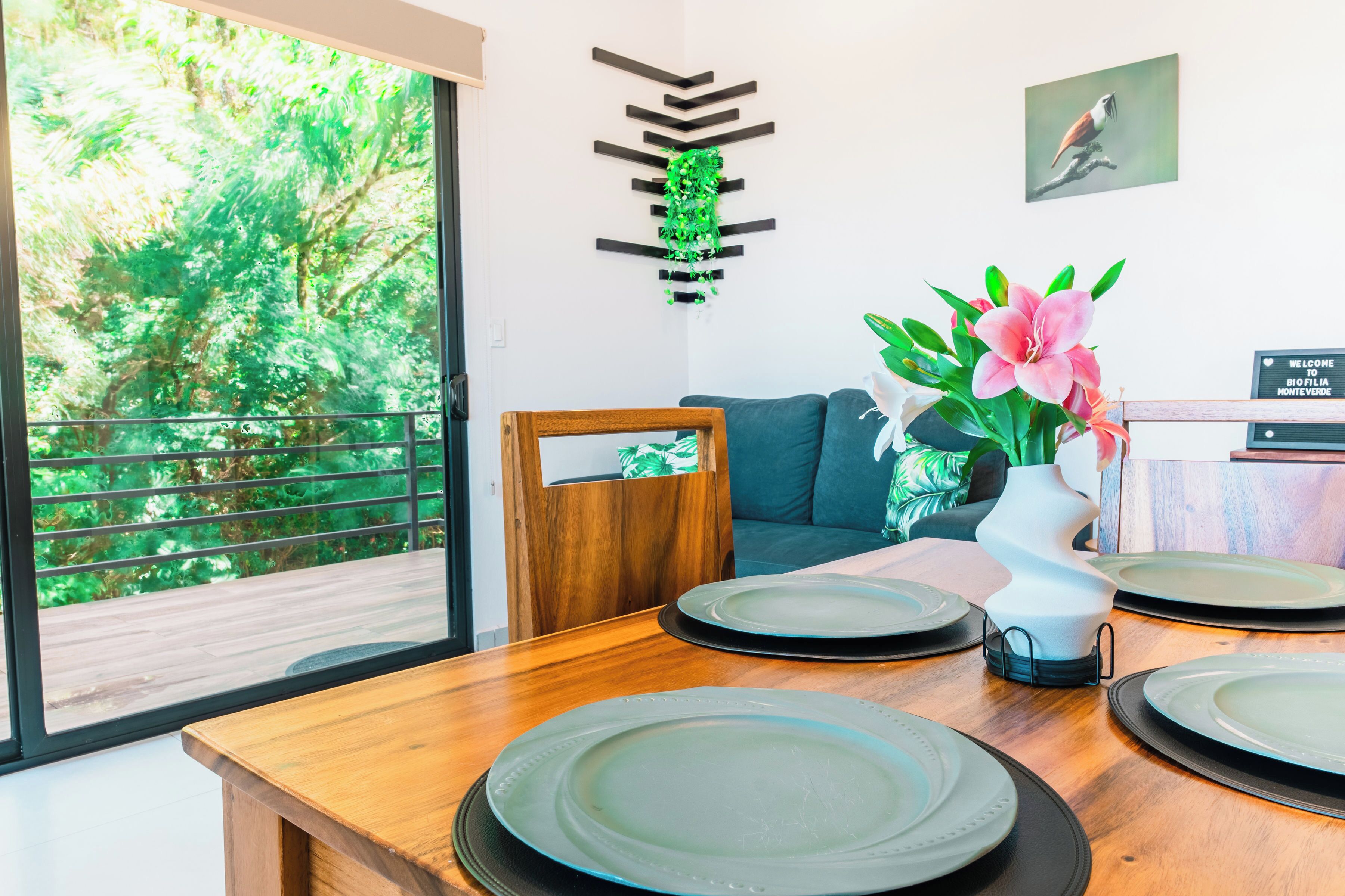 A dining area with a wooden table, plates, and a vase with flowers.