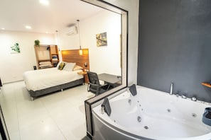 A modern bedroom with a bed, a wooden wardrobe, a desk, and a large bathtub. - Biofilia Monteverde (Monteverde)