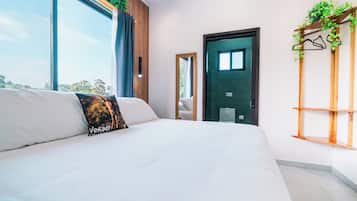 Un dormitorio moderno con una cama grande, vistas al exterior y una estantería de madera con plantas.