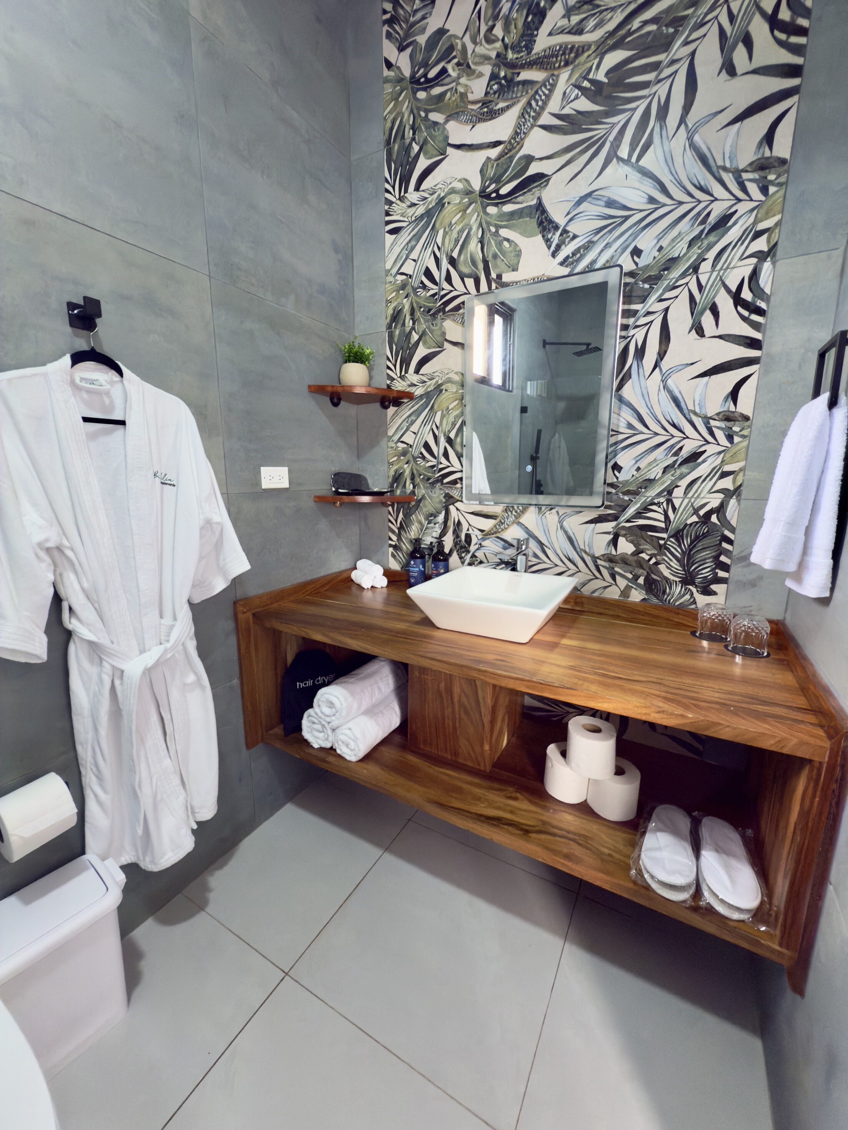 A bathroom with a wooden vanity, a large mirror, a sink, and a shower area.