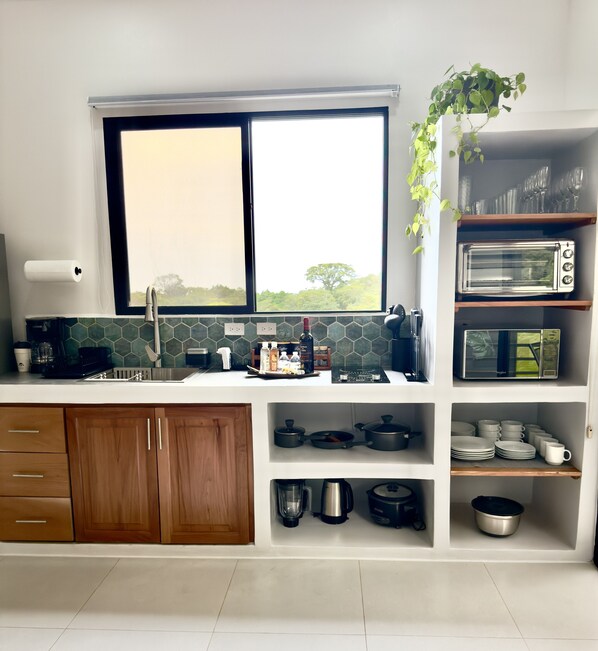 A modern kitchen with a large window, wooden cabinets, and various appliances including a toaster and a blender. - Biofilia Monteverde (Monteverde)