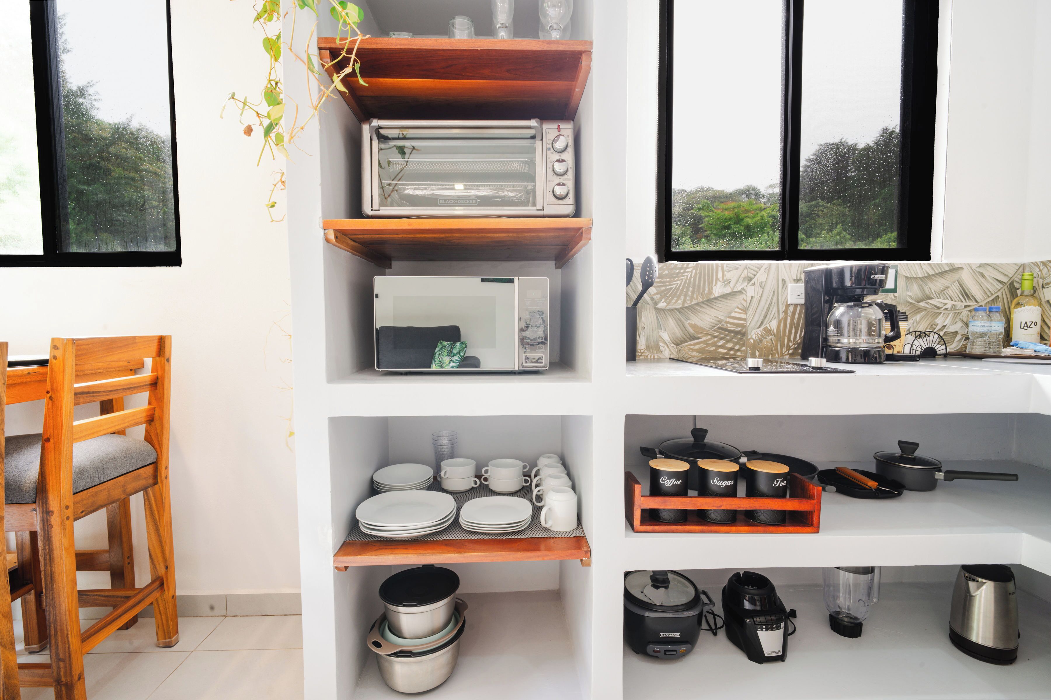 A kitchen with a microwave, toaster, and coffee maker on the countertop, and a wooden chair to the left.