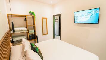 Un dormitorio con cama, armario, espejo, televisor y puerta.