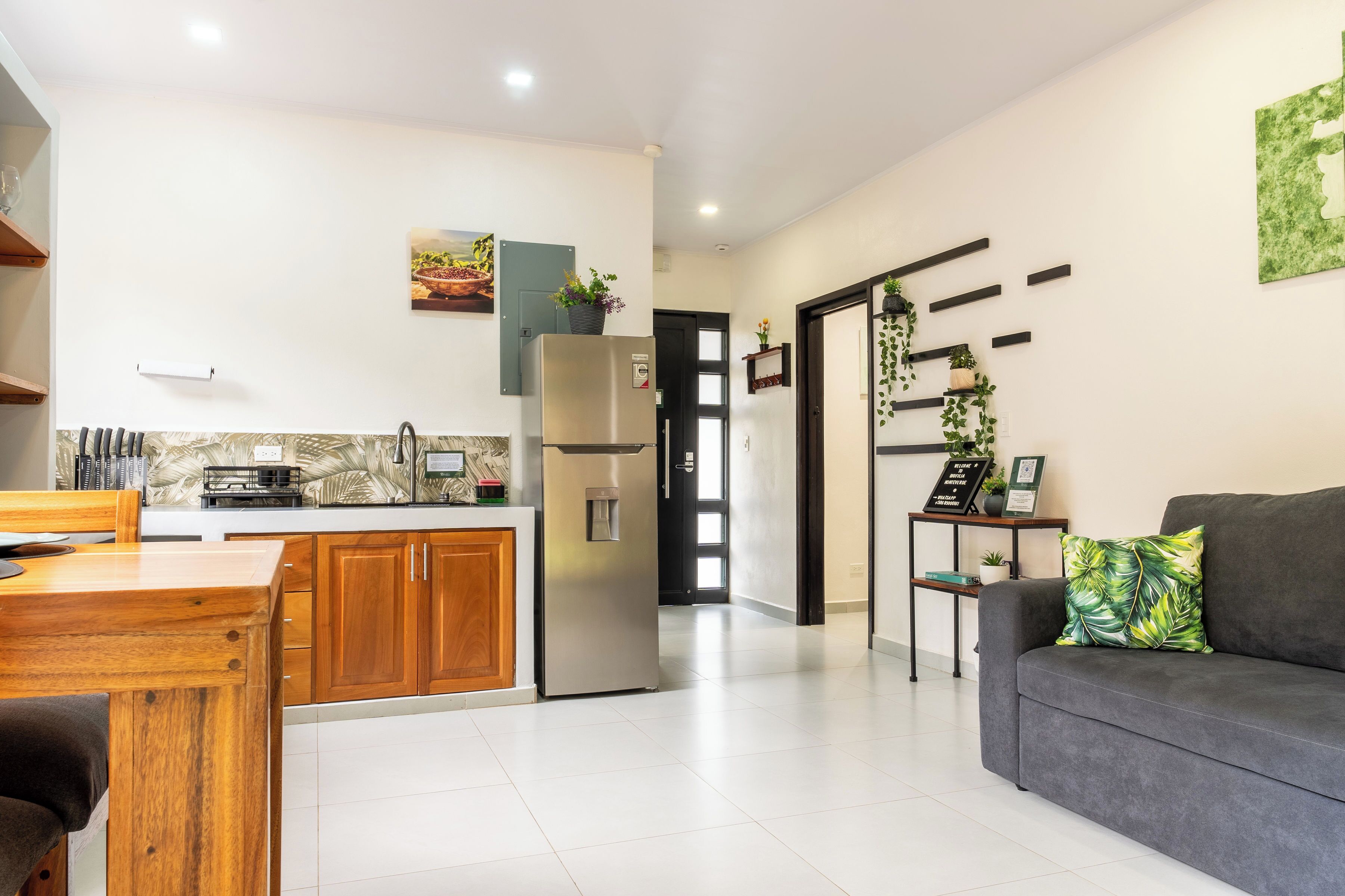 A modern kitchen with a refrigerator, wooden cabinets, and a dining area with a table and chairs.