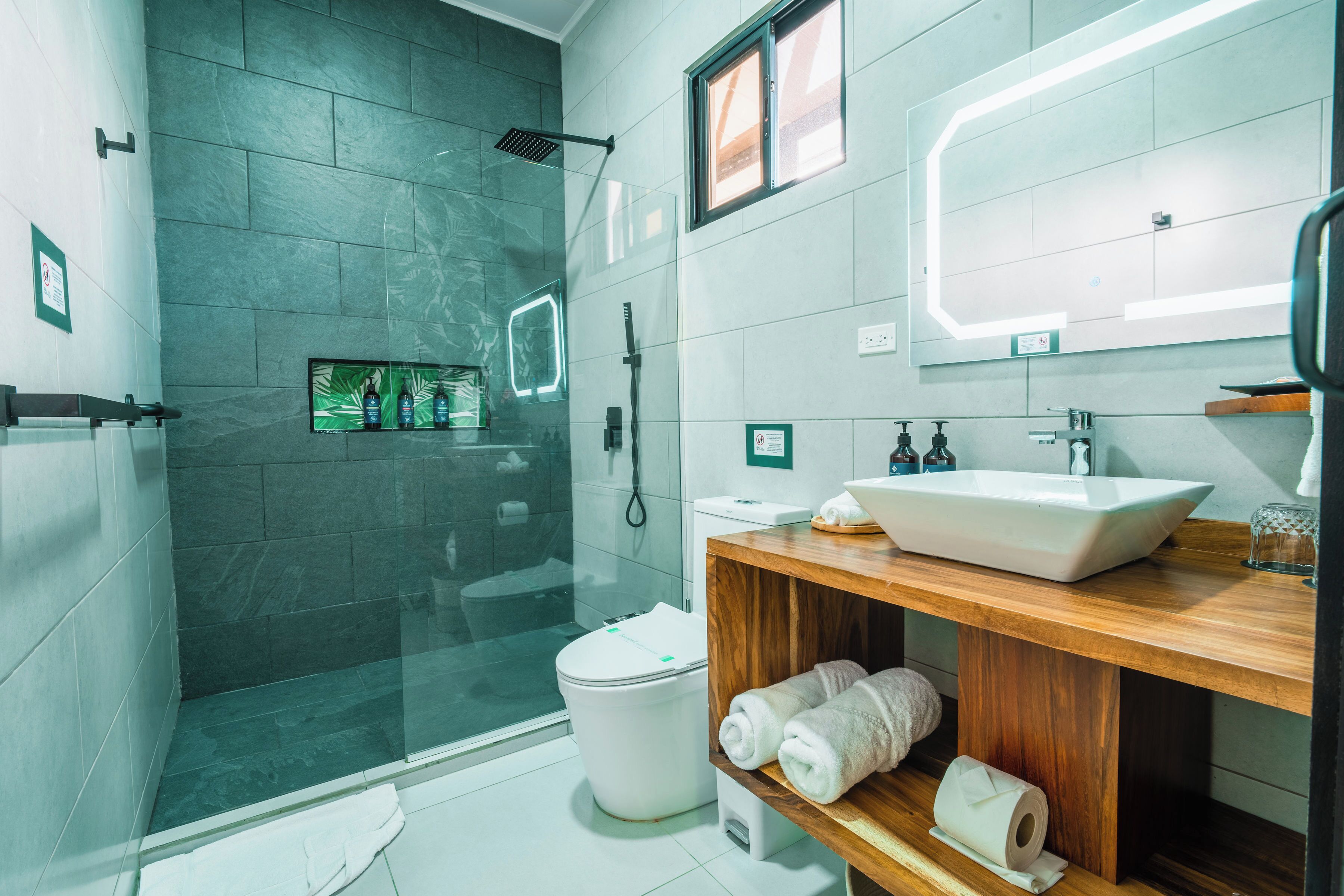 A modern bathroom with a glass-enclosed shower, a white sink, and a wooden vanity.