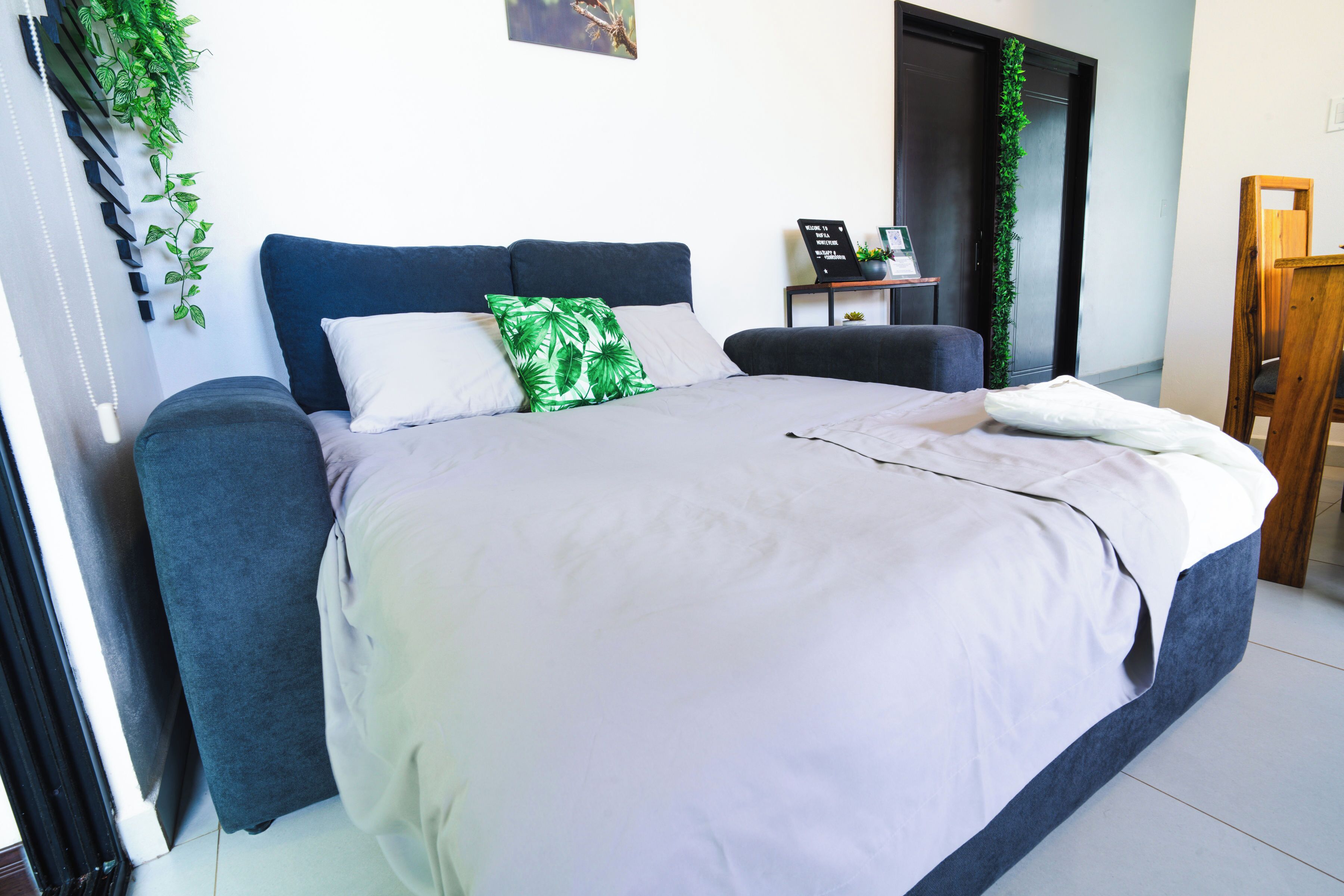 A bedroom with a bed, a bedside table, a chair, and a door.