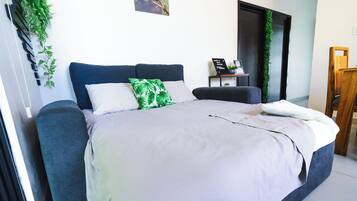A bedroom with a bed, a bedside table, a chair, and a door.