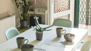 A dining area with a white table, green chairs, a potted plant, and a window with a view of a fence and palm trees. - Victory Suite, quiet a few minutes from downtown, with private parking (Firenze)