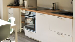 A modern kitchen with white cabinets, a wooden countertop, and a built-in oven. There are two potted plants on the upper cabinets. - Victory Suite, quiet a few minutes from downtown, with private parking (Firenze)