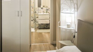 A bedroom with a bed, a wardrobe, a bedside table with a lamp, and a bathroom visible through an open door. - Victory Suite, quiet a few minutes from downtown, with private parking (Firenze)