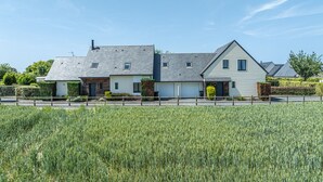 A two-story house with a garage, surrounded by a field.