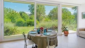 A dining area with a table set for four, large sliding glass doors, and a potted plant. - Apartment 2 with Lake View (Alvignano)