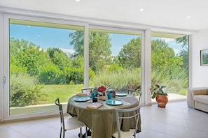 A dining area with a table set for four, large sliding glass doors, and a potted plant. - Apartment 2 with Lake View (Alvignano)