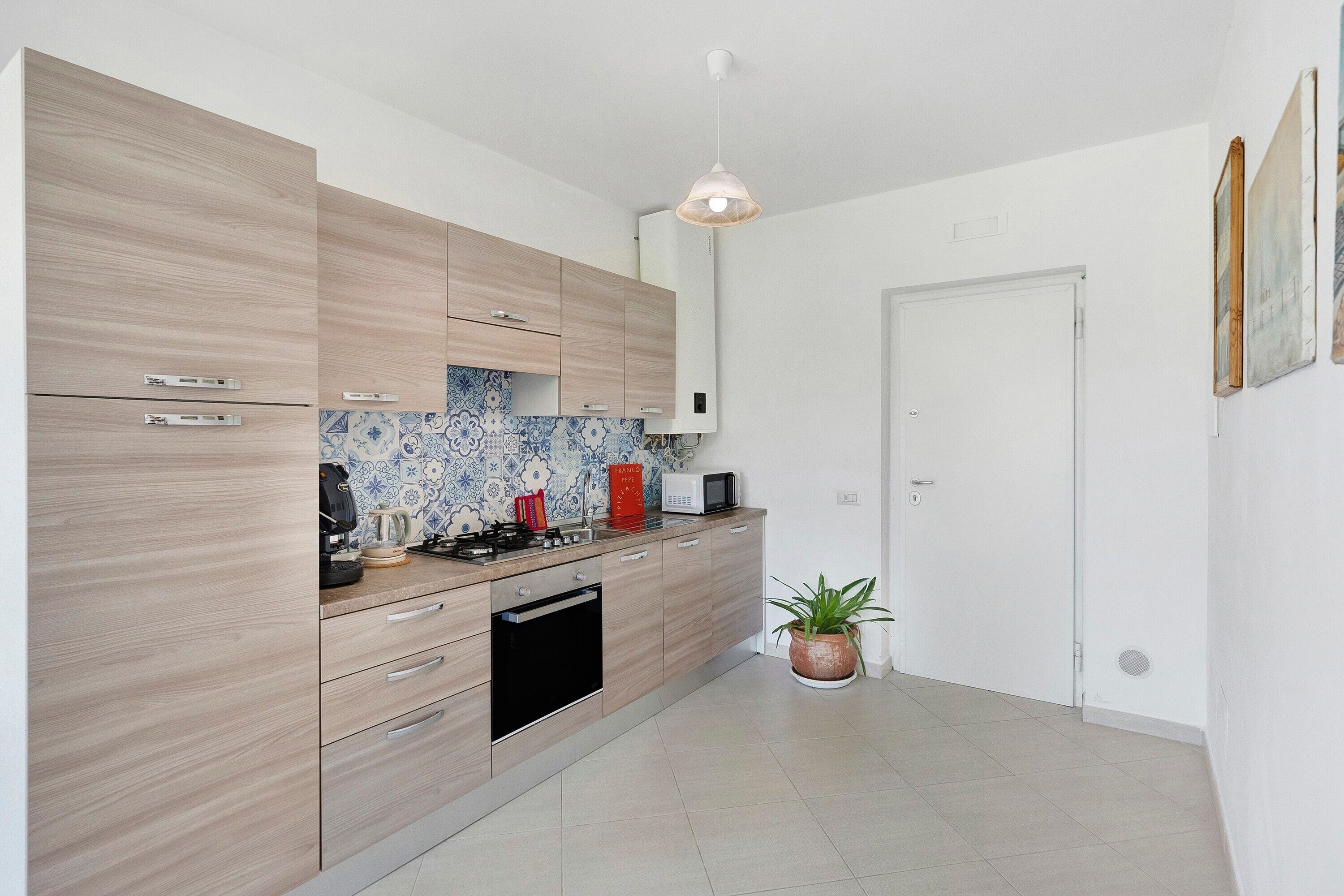 A modern kitchen with wooden cabinets, a microwave, a stove, and a sink.