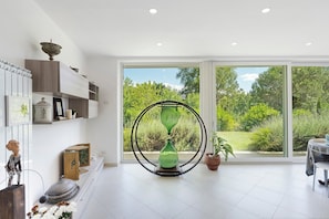 Un intérieur moderne avec une grande fenêtre, un sablier vert et un coin repas.
